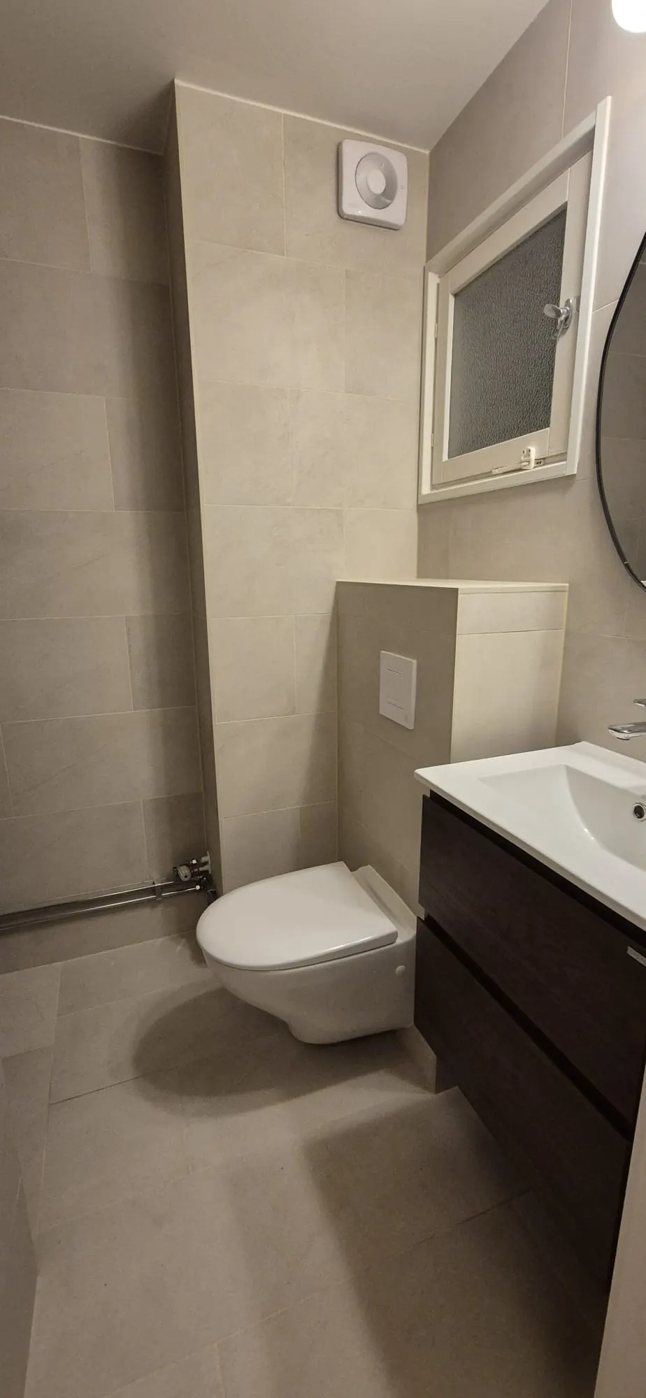 Stilrent gästbadrum i beige med vägghängd WC